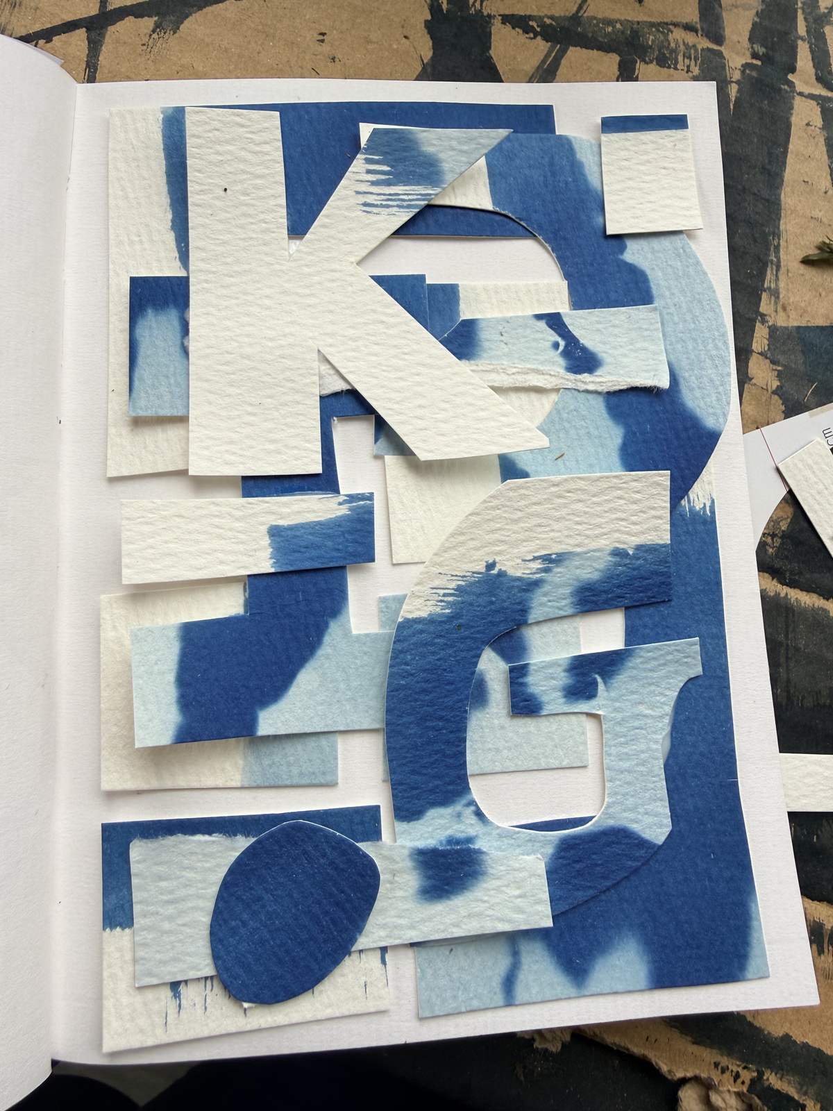 A collage of pale cut-paper letters over a blue cyanotype ground, the shapes never quite forming a word