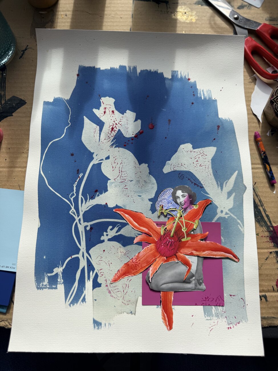 A cyanotype in deep blue with white botanical silhouettes, a single orange lily and a small seated figure