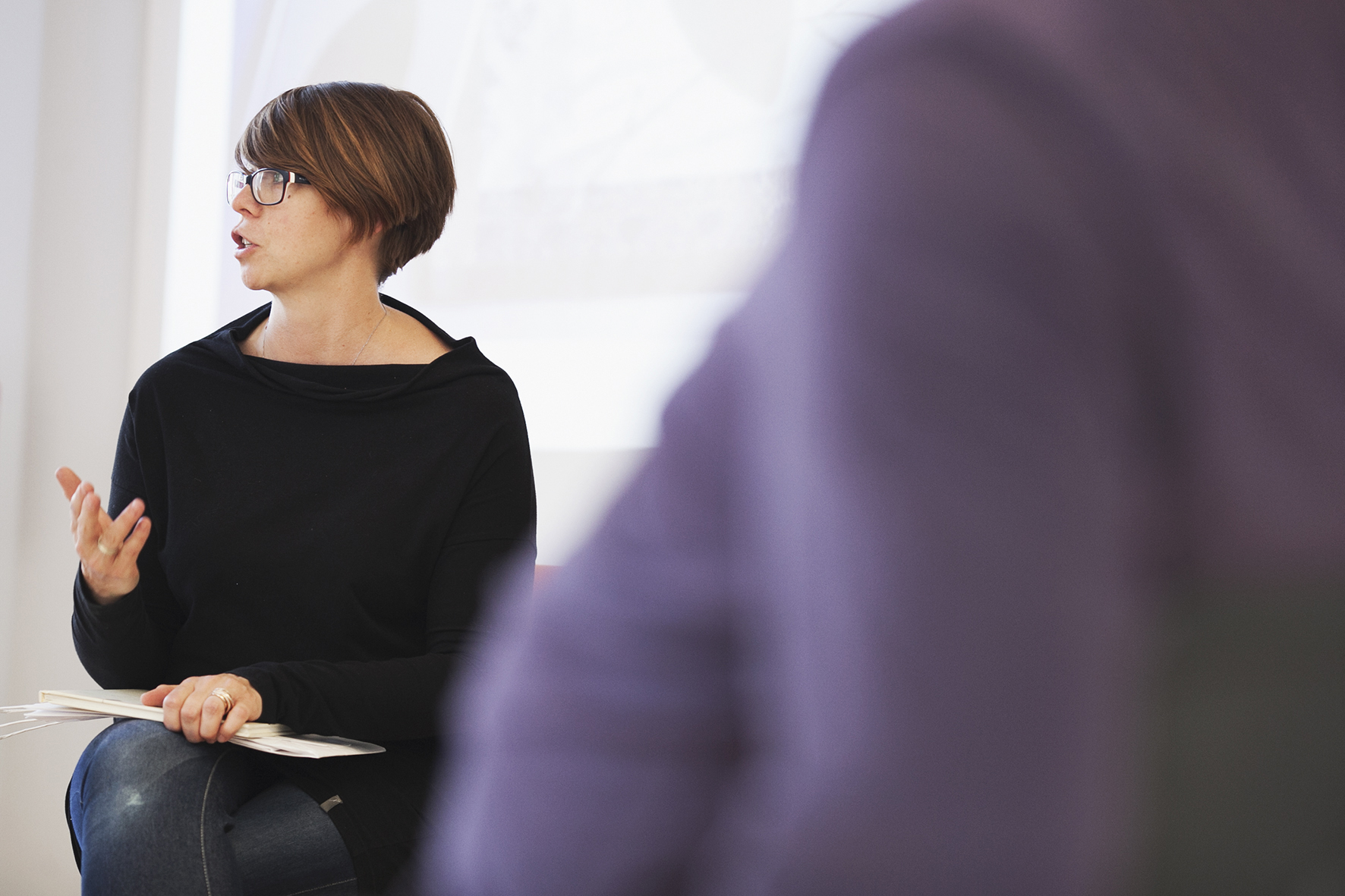 Kasia Nowacka listening closely during a coaching session, a client in soft focus in the foreground