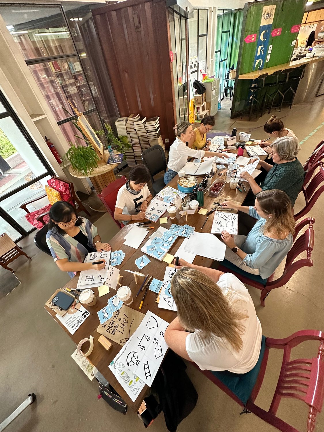 A group working with drawing and visual journaling around a long table in a warm studio